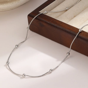 Elegant stainless steel silver necklace with beads displayed on a wooden jewelry tray