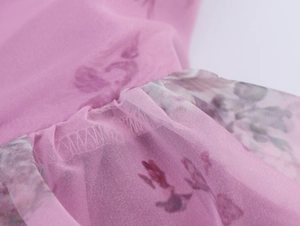 Detail of pink floral organza fabric with soft purple flower prints and mesh texture