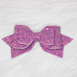 Close-up of glitter purple bow accessory for tumblers on white faux fur background