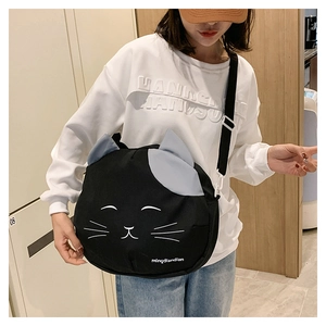 Detail of black canvas cat bag with 3D ears and white embroidery on a crossbody strap