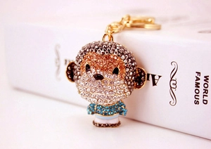 Detailed view of a golden rhinestone monkey keychain on a decorative book background