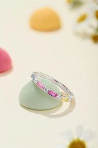 Macro detail of silver ring with colorful rectangular crystals on light green pebble