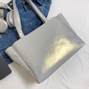Silver glossy tote bag with reflective leather finish styled with denim jacket