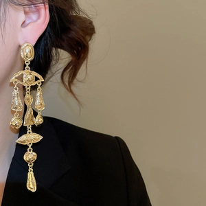 Detail of vintage gold tassel earrings featuring abstract face motifs and hammered texture