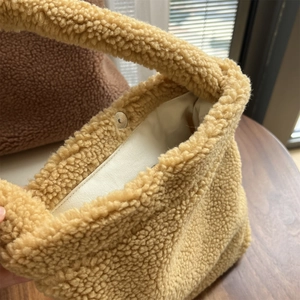 Detail of plush faux shearling bag featuring magnetic buckle and soft texture