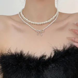 Double-layered pearl necklace with zircon bow pendant worn on a model in elegant style