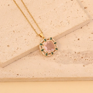 Gold pendant necklace with pink crystal center and green drop accents on stone