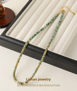 Detail of green stone beads and gold metal spacers on adjustable necklace on jewelry tray