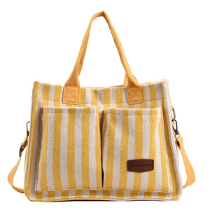 Yellow and white striped canvas tote bag with front pockets and long shoulder strap