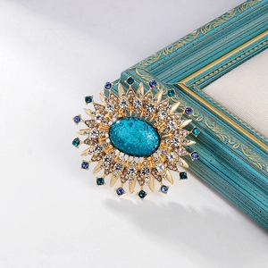 Close-up of vintage sunburst brooch with turquoise stone and sparkling crystals