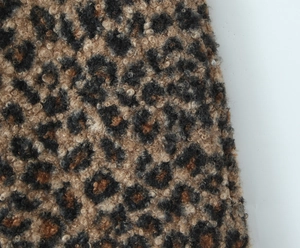 Gros plan du tissu de jupe léopard montrant la texture épaisse de la laine bouclée