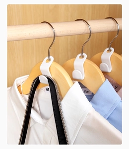 Close-up of white plastic clothes hanger connector hook on a wooden hanger for space saving