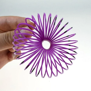 Close-up of purple rainbow spring toy with black stripes being stretched by hand