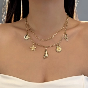 Detail of gold layered necklace with shell, starfish, and seahorse pendants on a model