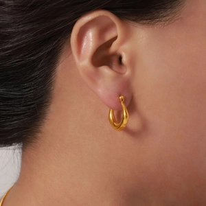 Boucles d'oreilles créoles en acier inoxydable plaqué or portées sur l'oreille d'un mannequin