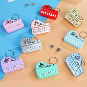 Mini piano keyboard toy keychain in various metallic colors with music notes and light-up keys