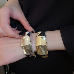 Detail of liquid metal textured bangles in gold and silver finish with wavy design