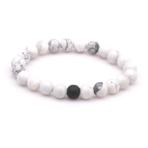 Detailed macro view of white turquoise beads with grey veins and black lava stone bead
