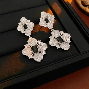 Macro shot of silver flower earrings with white crystals and black rectangle gem center
