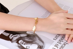 Gros plan du bracelet doré avec pendentif petite fille et fermoir homard sur un magazine