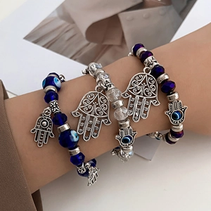Detailopname van kralenarmbanden met Hand van Fatima en boze oog bedels om de pols