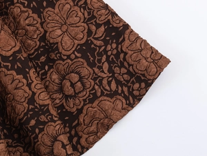 Gros plan sur le tissu jacquard marron foncé à motifs floraux en relief d'une robe