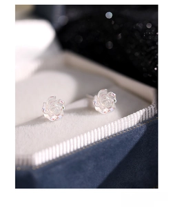 Macro detail of S925 sterling silver white iridescent rose earrings in a blue jewelry box
