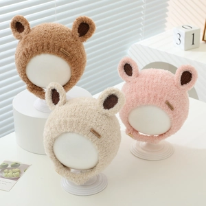 Detail of plush baby winter hats with bear ears in brown, pink, and beige soft teddy fleece