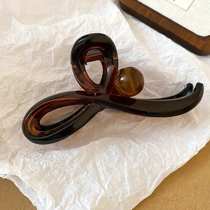 Détail d'une grande pince à cheveux écaillée avec ressort métallique sur papier d'art