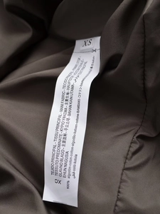 Detailed macro view of internal care label and XS size tag on 100% cotton coat