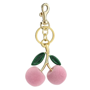 Pink plush cherry keychain with green metal leaves and gold lobster clasp on white background