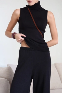 Detail of minimalist black high neck knitted vest and matching straight leg trousers set