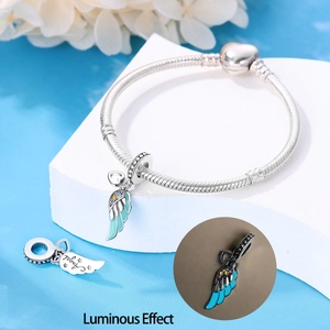 Detailed view of silver angel wing charm with blue enamel and luminous effect on bracelet
