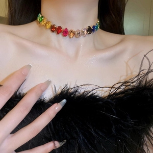 Detail of a luxury gold-plated necklace featuring multi-colored teardrop crystal stones