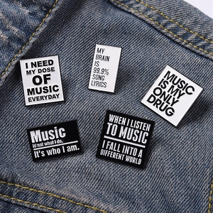 Set of 5 black and white music quote enamel pins displayed on blue denim fabric