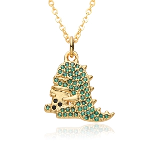 Detailed macro shot of a golden dinosaur necklace with sparkling green zircon stones