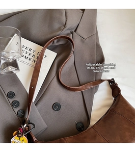 Detail of brown vintage crescent bag with adjustable strap and smile pendant