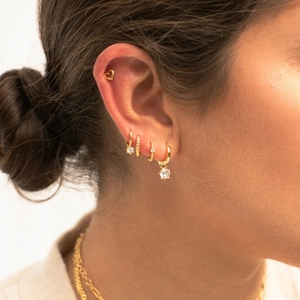 Set de pendientes dorados con circonitas en modelo mostrado en vista de perfil