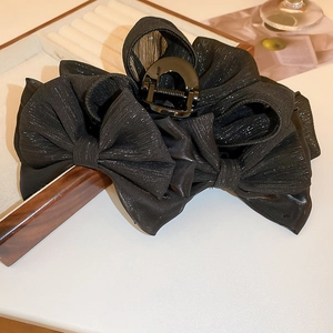Gros plan d'une grande pince à cheveux nœud noir élégante avec texture scintillante