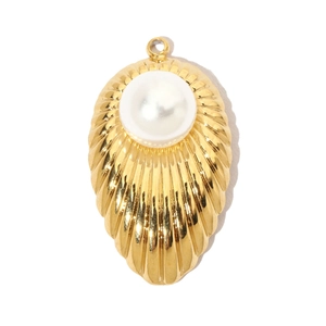 Detail of a golden shell pendant featuring a glossy white pearl and refined textures