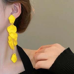 Macro detail of elegant yellow flower petal tassel earrings worn by a female model