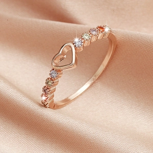 Macro detail of rose gold heart ring with colorful gemstones on silk background