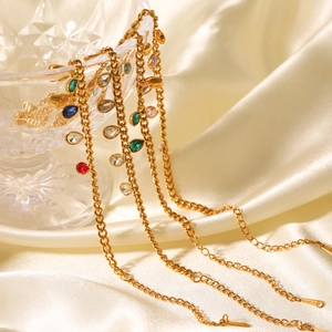 Detailed view of golden chain necklace with colorful teardrop zircons on silk background