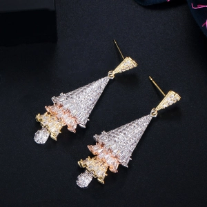 Macro view of triple-tone tiered earrings with micro-set zircons on dark background