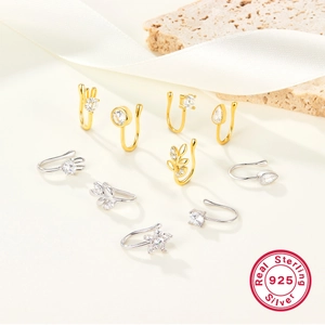 Macro detail of 925 sterling silver star nose studs and ear clips in gold and silver
