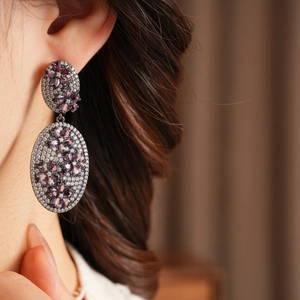 Detailed view of vintage zircon flower earrings in black metal on model's ear