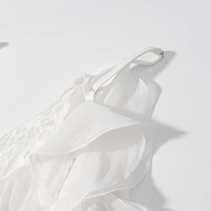 Détail de robe blanche en mousseline et dentelle avec volants et bretelles