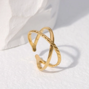 Minimalist gold adjustable open cross ring displayed on white textured stone background