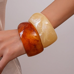 Detail of chunky resin bangles in amber tortoiseshell and creamy marble finishes