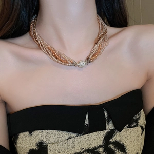 Close-up of layered beaded necklace in brown and gold on model neckline detail